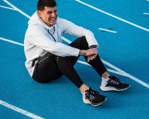 Benjamin Robert, assis sur une piste d'athlétisme en tartan bleu, après une séance d'entrainement avec des Nike Zoom Pegasus 38 aux pieds.